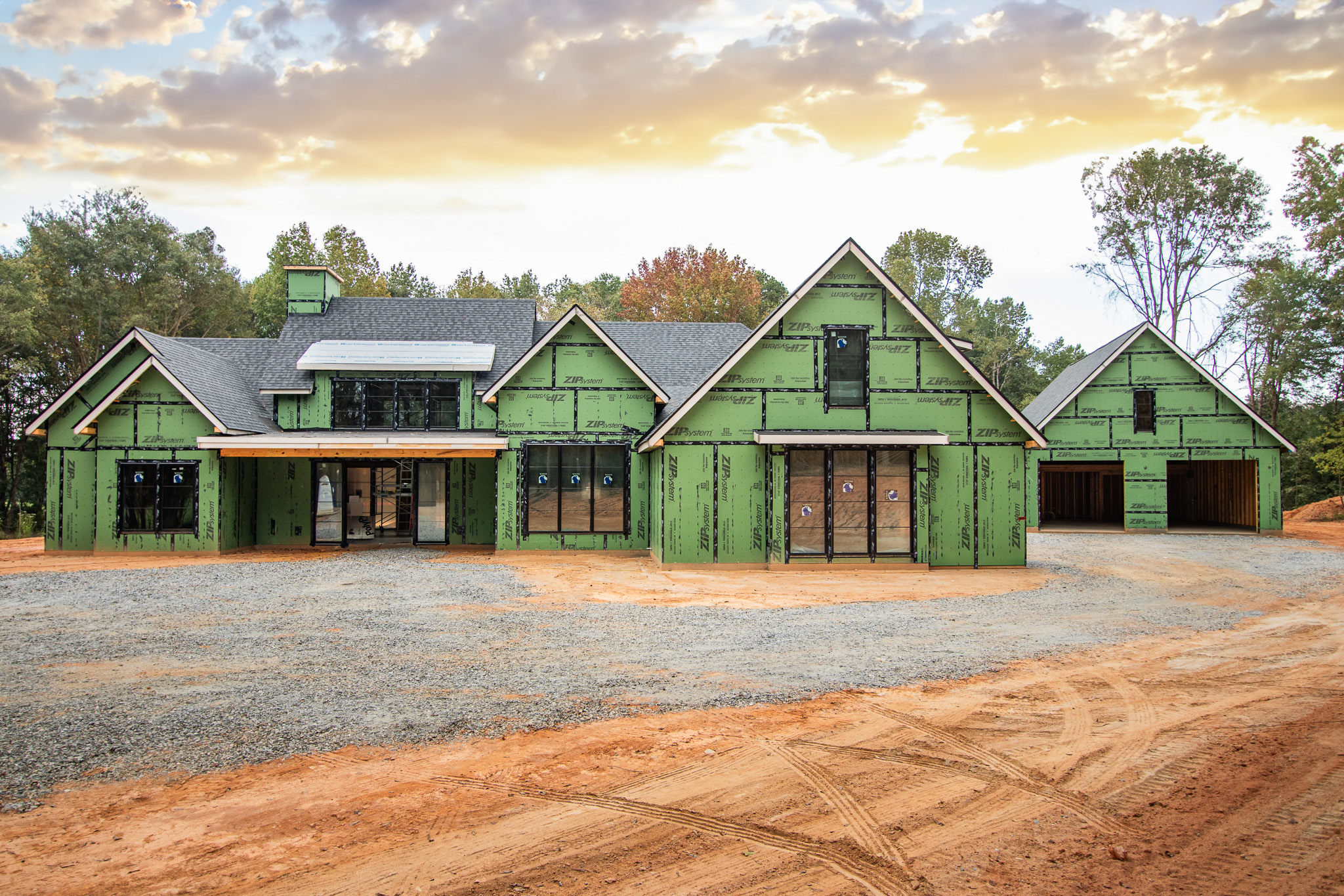 Custom home under construction showing ZIP System building envelope with green sheathing across roof and walls